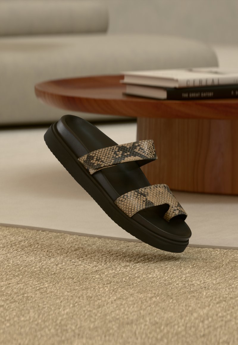 Μαύρο σανδάλι πλατφόρμα με δύο ραβδώσεις με υφή και σχέδιο φίδι. Η σόλα είναι λεία και ματ, σε αντίθεση με το διακοσμημένο επάνω μέρος.