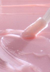 Lippenpflege-Tube mit einer weichen, durchscheinenden pinkfarbenen Geltextur, aufgetragen mit einem wolligen Applikatorstab. Glatte Oberfläche mit dezentem Glanz.