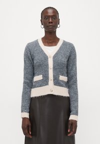Cardigan grigio e beige chiaro con scollo a V, bottoni perle, due tasche frontali e polsini e orlo a coste. Materiale in maglia con una texture morbida.