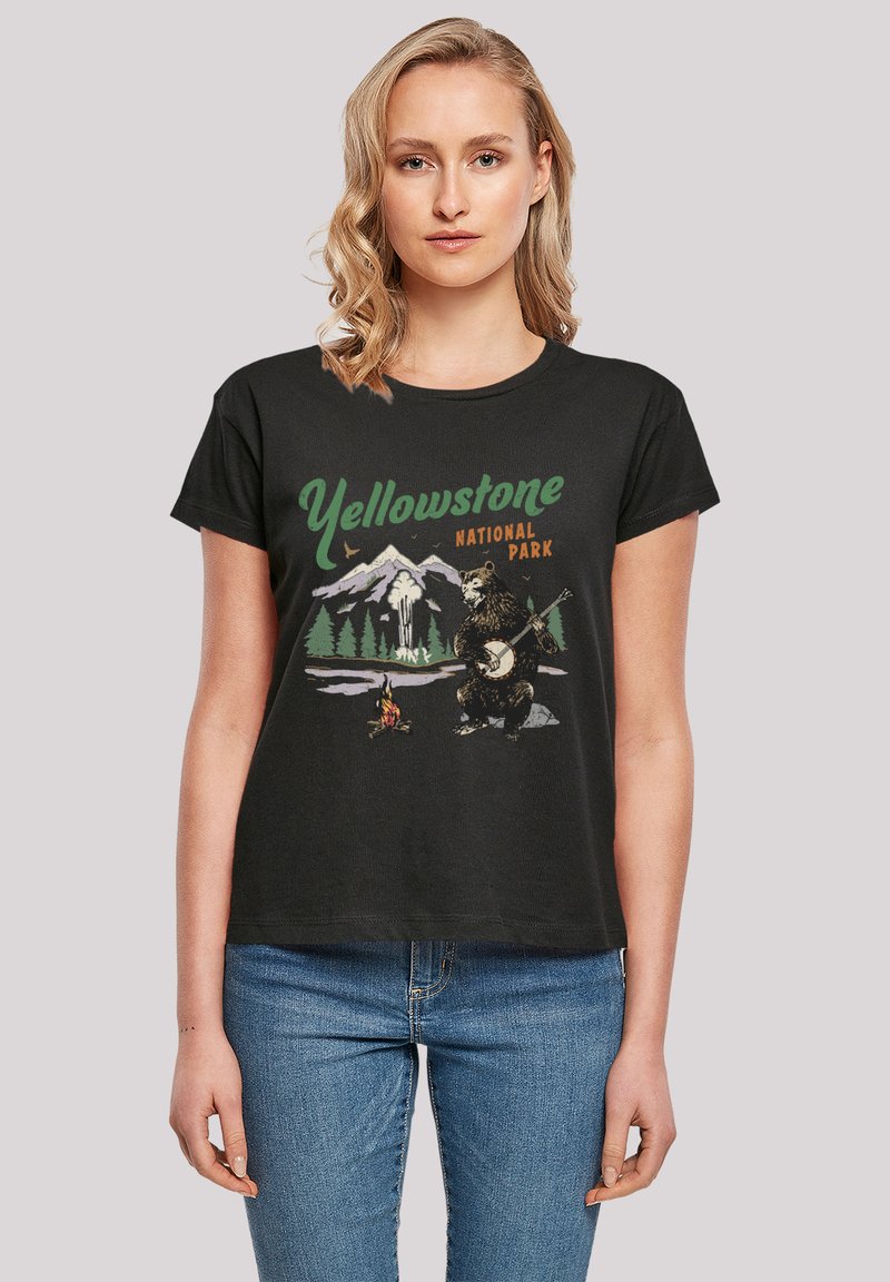 Schwarzes Baumwoll-T-Shirt mit einem grafischen Druck eines Bären, der Banjo spielt, mit Bergen und Bäumen, beschriftet mit "Yellowstone Nationalpark."