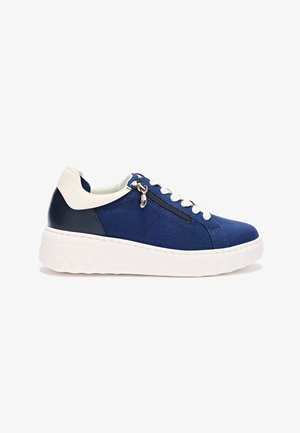Lage sneaker in marineblauw met een witte zool, witte veters, een witte hielstrook en een zijrits, tegen een effen witte achtergrond.