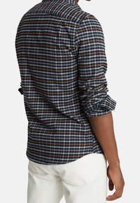 Långärmad rutig skjorta med en marinblå bas och blå, vita och bruna ränder. Tillverkad av mjukt tyg med en avslappnad passform och uppvikta ärmar.