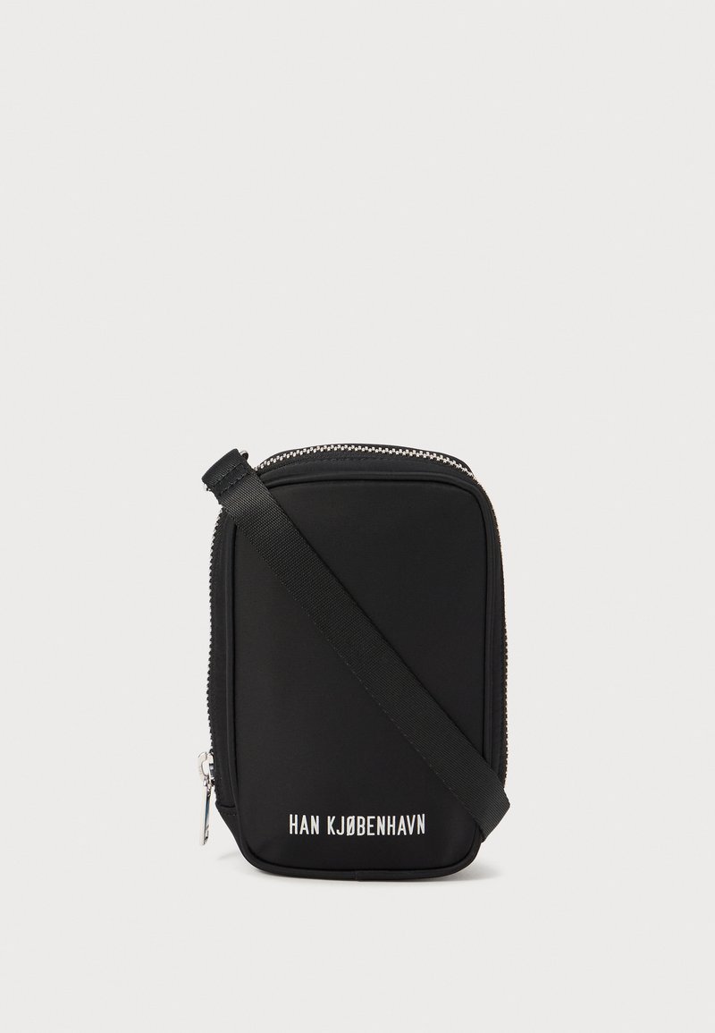 Black bag with a rectangular shape, made of smooth material. Features a top zipper, adjustable strap, and white text: "HAN KJØBENHAVN."