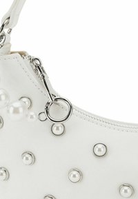 Borsa in similpelle bianca con hardware argentato, caratterizzata da decorazioni di perle rotonde e chiusura con zip per un accesso sicuro.