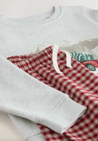 Grå sweatshirt med lange ærmer og ribbede manchetter, parret med røde og beige ternede pyjamasbukser med elastisk talje.
