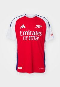 Maillot de football rouge et blanc à manches courtes, portant le logo "Emirates FLY BETTER", des bandes Adidas et le blason d'Arsenal. TEXTURE : lisse.