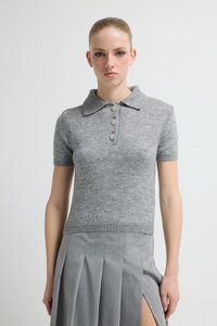 Grijze korte mouw polo trui gemaakt van zachte stof, met een kraag en drie decoratieve knopen. De pasvorm is nauwsluitend en cropped.