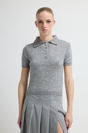 Grijze korte mouw polo trui gemaakt van zachte stof, met een kraag en drie decoratieve knopen. De pasvorm is nauwsluitend en cropped.