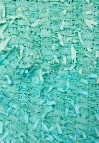 Textilmaterial in teal mit einer strukturierten Webart aus Schlaufen und bandartigen Akzenten, die eine geschichtete, taktile Oberfläche schaffen.