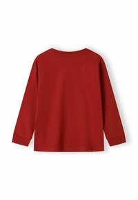 Vienkārša garā piedurkne sarkana crewneck krekls izlikts plakani no aizmugures, parādot ribotas piedurknes un apakšmalas šuvju.