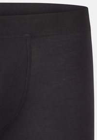 Svarta bomullsboxer med en mjuk yta, elastisk midja och förstärkta sömmar. Nära vy framhäver tygets hållbarhet och design.