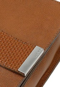 Hnědá kožená kabelka s texturovaným panelem a elegantními stříbrnými prvky. Design obsahuje hladké tělo a detailní švy.