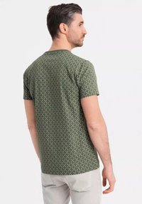 Zelené tričko s krátkým rukávem se vzorem diamantů v světlejším odstínu, vyrobené z měkké látky s volným střihem.