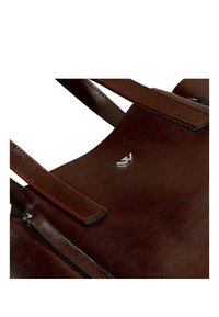 Hnědá kožená kabelka se dvěma robustními uchy, s charakteristickým stříbrným logem, hladkým povrchem a minimalistickým designem.