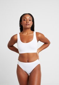 Vitt bh och matchande högmidjade bikinitrosor i mjukt, elastiskt tyg. Bh:n har breda band och en rundad urringning.