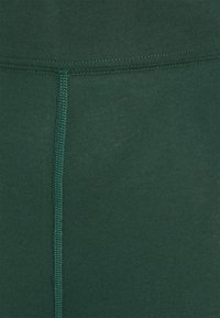 Gröna ribbade leggings i tyg med en slät yta, platta sömmar och hög midja, designade för komfort och flexibilitet.