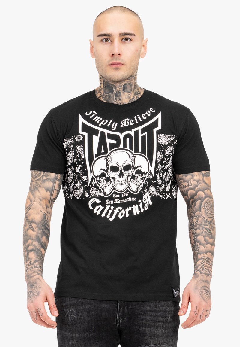 Fekete pamut póló fehér koponya grafikákkal, "TAPOUT" felirattal és bandana-stílusú díszítésekkel. Rövid ujjú és kerek nyakú dizájn.