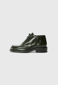 Dark green leather shoes with a glossy finish, featuring a rounded toe, contrasting stitching, and a low block heel. Lace-up design.
