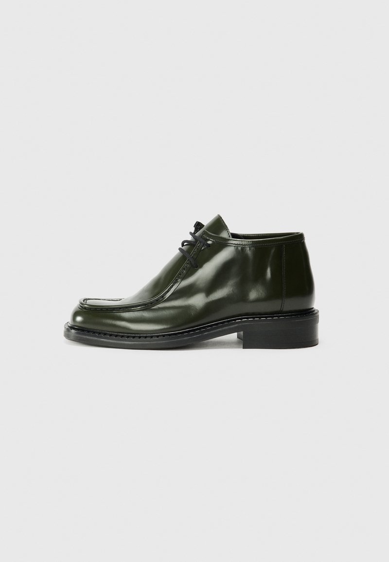 Dark green leather shoes with a glossy finish, featuring a rounded toe, contrasting stitching, and a low block heel. Lace-up design.