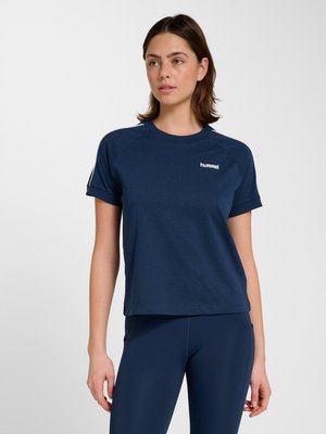 Kvinde iført en mørkeblå hummel kortærmet t-shirt og matchende leggings, stående mod en ensfarvet lys baggrund.