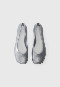 Ballerines en argent scintillant avec un bout arrondi, un matériau flexible et une doublure intérieure lisse. Semelle plate simple pour le confort.