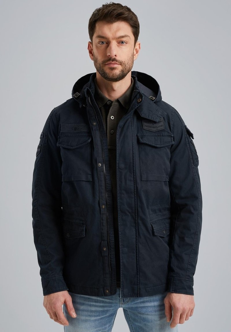 Giacca blu navy realizzata in tessuto testurizzato, con cappuccio, diverse tasche frontali e dettagli con bottoni. Adatta per un abbigliamento casual.