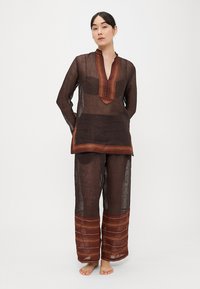 Hnedý ľanový set tuniky a nohavíc s vertikálnymi pruhmi v červenej a oranžovej farbe, s golierom a voľným strihom.