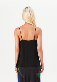 Camisola in satin nero con spalline sottili e vestibilità rilassata, caratterizzata da una superficie liscia e un orlo dritto sul retro.