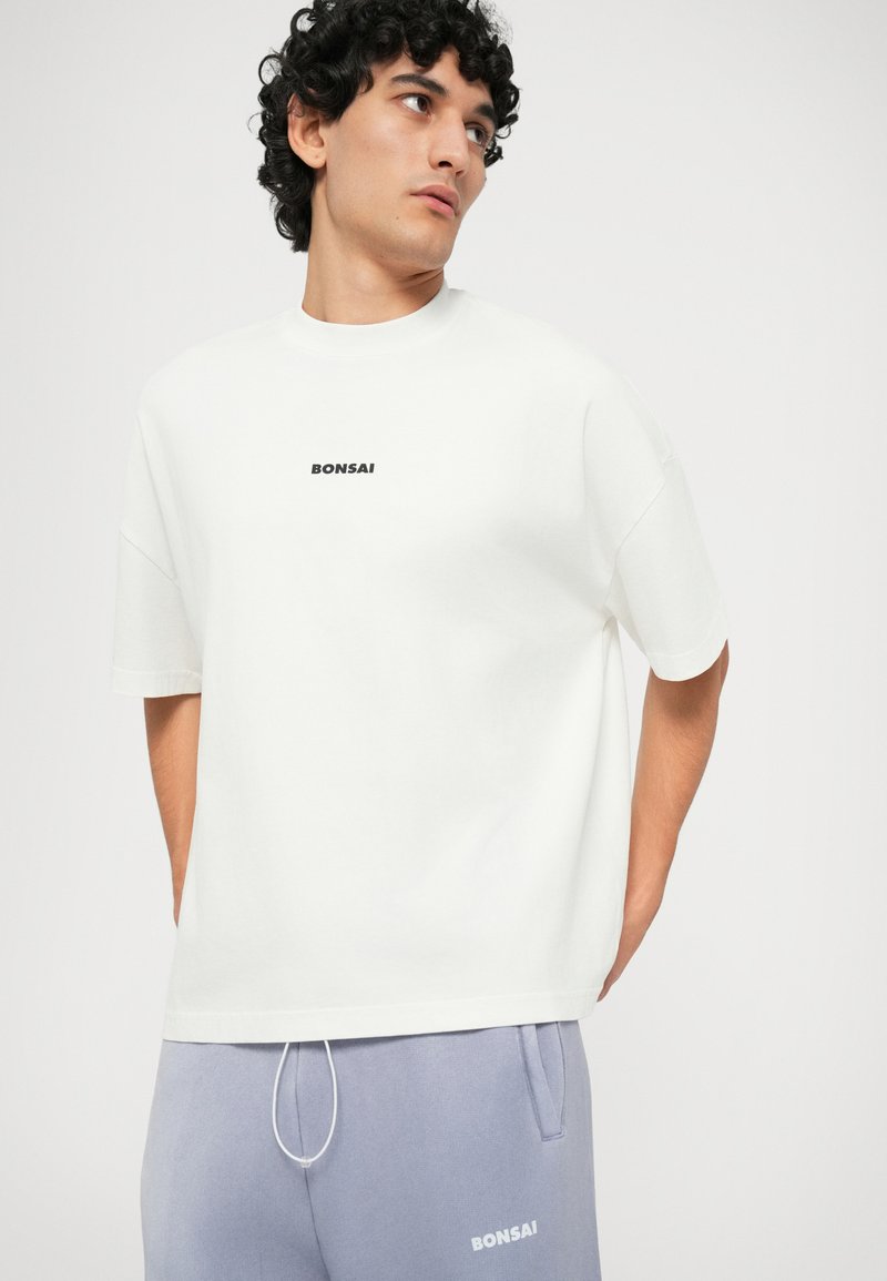 White cotton t-shirt with short sleeves and a crew neck, featuring a black "BONSAI" logo at the center. Smooth texture, relaxed fit.