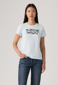 Ανοιχτό μπλε βαμβακερό t-shirt με λουλουδάτο λογότυπο Levi’s σε μαύρο και άσπρο στο μπροστινό μέρος, στρογγυλή λαιμόκοψη και κοντά μανίκια.