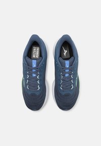 Scarpe da corsa color blu navy con tomaia in mesh, accentuazione verde del logo e suola bianca. Presentano un collare imbottito e lacci piatti. Marchio MIZUNO sulla soletta.