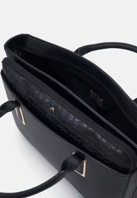 Bolso tote de cuero negro con un forro interior texturizado, herrajes en tono dorado, asas dobles y compartimentos con cremallera para la organización.