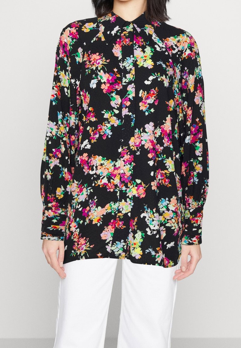 Floral blouse with black background, featuring vibrant pink, yellow, and green flowers, buttoned front, and long, puffed sleeves.