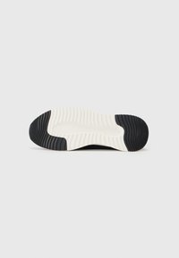 Talpă de sneaker alb-negru cu striații texturate, având o bază albă netedă și o margine de cauciuc negru profund.