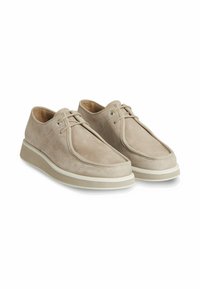 Scarpe in suede beige con una texture liscia, caratterizzate da una punta rotonda, cuciture sottili e una suola in gomma bianca con leggera ammortizzazione.