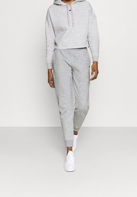 Szara, krótka bluza z kapturem i sznurkiem, w zestawie z szarymi dresami. Obie wykonane z miękkiego materiału, z ściągaczami i akcentem z logo.