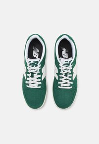 Green suede sneakers with white accents and perforations. Features white laces and black insoles with logo. Classic low-top design.