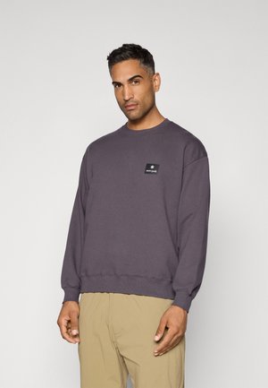 Felpa viola in cotone, con collo rotondo, maniche lunghe e una piccola etichetta logo nera sul petto. Texture liscia.