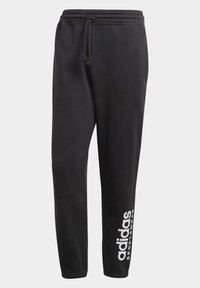 Pantaloni della tuta neri con vita elastica e coulisse regolabile. Presentano il logo bianco "adidas" e il testo "SPORTSWEAR" sulla gamba sinistra.