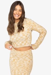 Gehaakte tweedelige set bestaande uit een cropped top met lange mouwen en een hooggepaste rok in een gele en crèmekleurige gemarmerde patroon met geribbelde manchetten.
