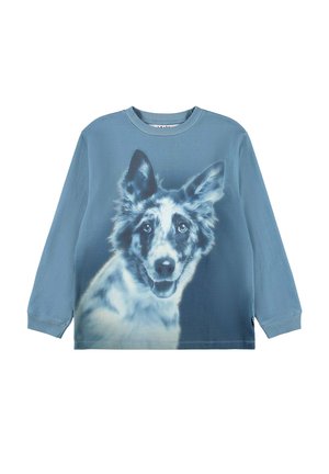 Blå skjorte med lange ærmer med et stort, detaljeret tryk af en glad sort og hvid hund med spidse ører på fronten.