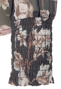 Blusa con motivo floreale caratterizzata da un tessuto trasparente, base grigio scuro, arricciature elastiche ai polsini delle maniche e bordi leggermente arricciati.
