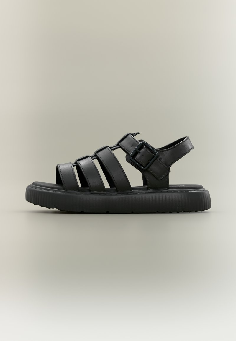 Μαύρο σανδάλι με τρεις φαρδιές λουρίδες και κούμπωμα με αγκράφα, διαθέτει υφασμένο πέλμα και επίπεδη σχεδίαση για άνεση και υποστήριξη.