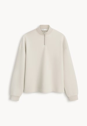 Beżowa bluza z długim rękawem z prążkowanymi ściągaczami na mankietach i kołnierzu, z przednim zamkiem błyskawicznym sięgającym do połowy długości od dekoltu.