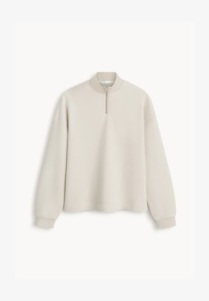 Beżowa bluza z długim rękawem z prążkowanymi ściągaczami na mankietach i kołnierzu, z przednim zamkiem błyskawicznym sięgającym do połowy długości od dekoltu.