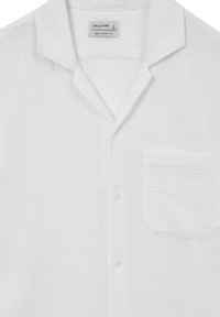 Camicia bianca oversize in tessuto testurizzato, con colletto, chiusura a bottoni e taschino sul lato sinistro.