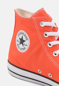 Hochschnittige orangefarbene Leinensneaker mit weißen Schnürsenkeln und Ösen. Verfügt über ein schwarz-weißes Sternlogo an der Seite und eine schwarze Gummisohle.