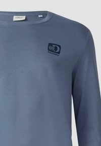 Langarmige blauwe shirt gemaakt van zachte stof. Beschikt over een ronde halslijn en een zwart Discovery-logo op de linkerkant van de borst.