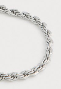 Σπαστή ασημένια αλυσίδα λαιμού με διασυνδεδεμένους βρόχους σε λευκό φόντο.