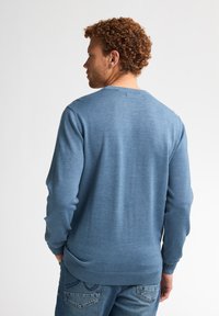 Blauwe ronde hals trui met lange mouwen, gemaakt van een gladde brei stof. Heeft een ribgebreide onderrand en manchetten voor een getailleerde look.